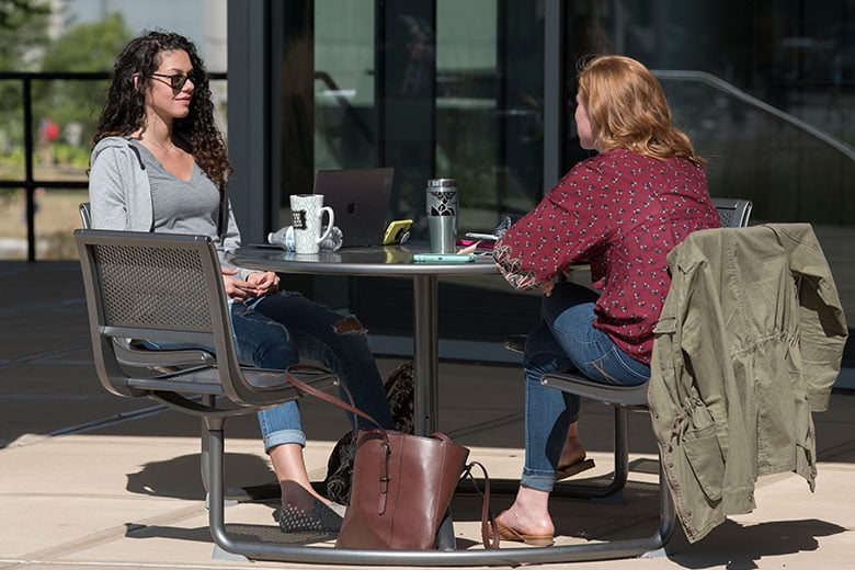 Two students sitting a table outside on NKU's campus.