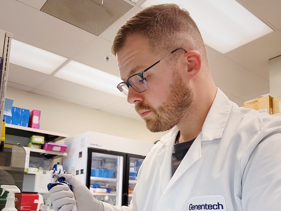 Student in lab coat working inside lab.