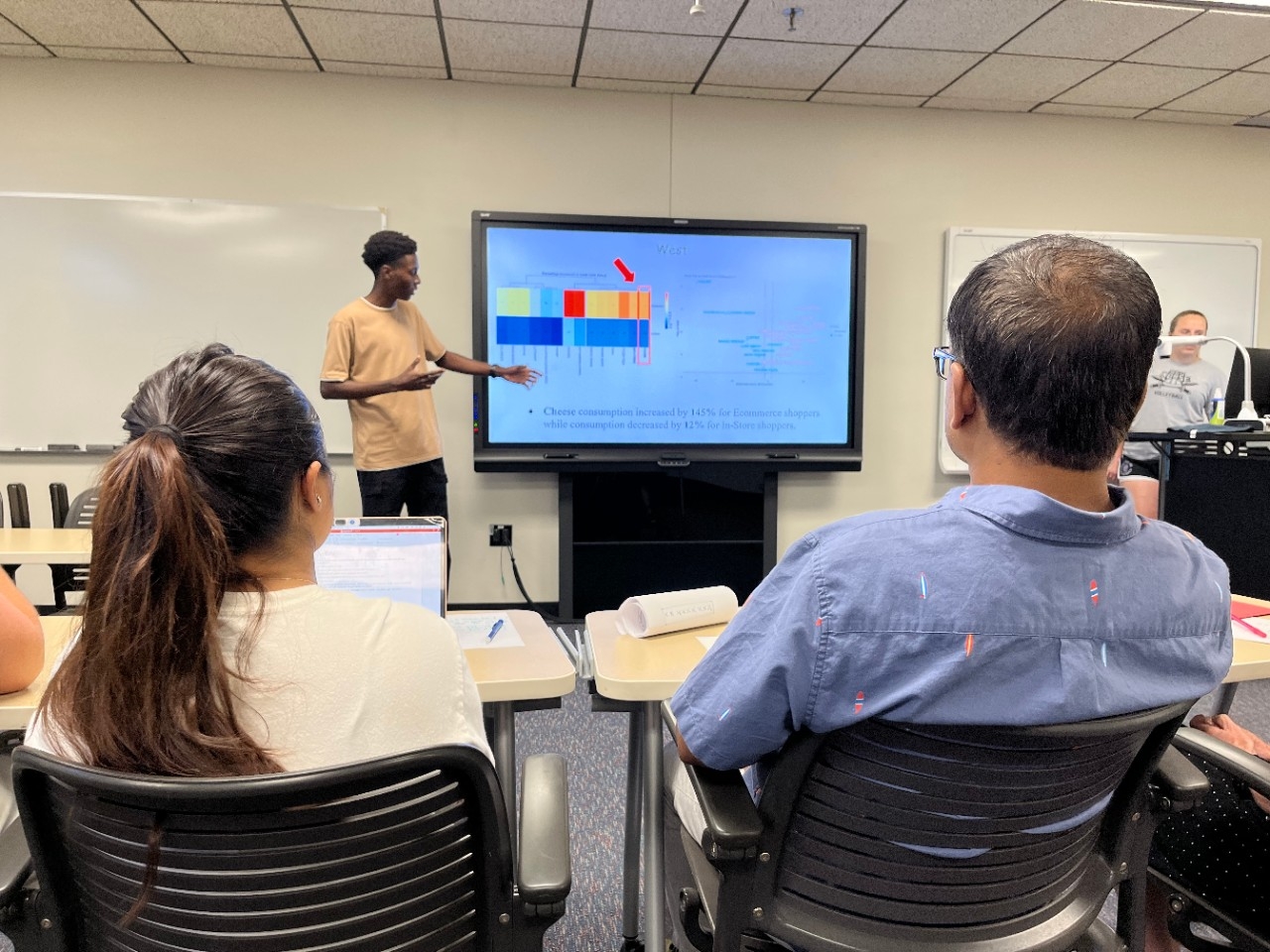 A student presents research data analysis to their research team in a classroom setting.