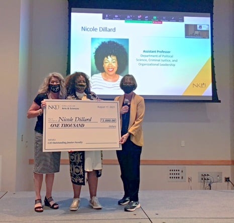 Drs. Karen Miller, Nicole Dillard, and Diana McGill on stage holding a large check 