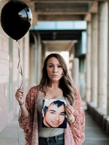 Gabi Deaton holding a black balloon and a photo