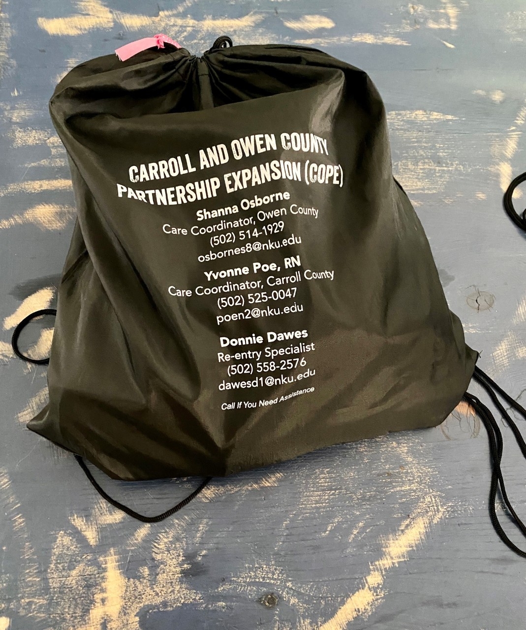 Black drawstring bag with resource information.