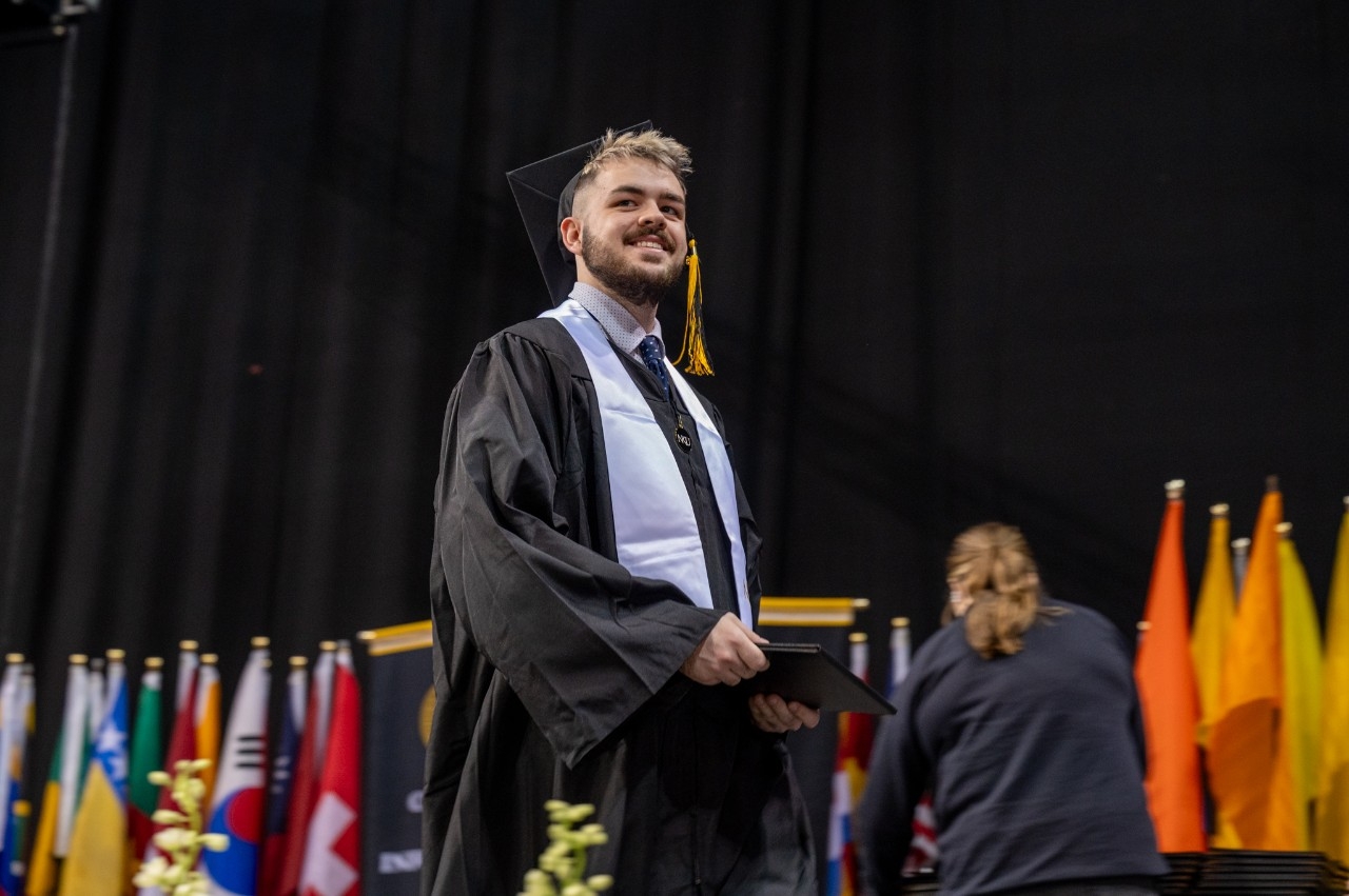 Student crosses the stage in Truist Arena at NKU's 54th commencement ceremony.